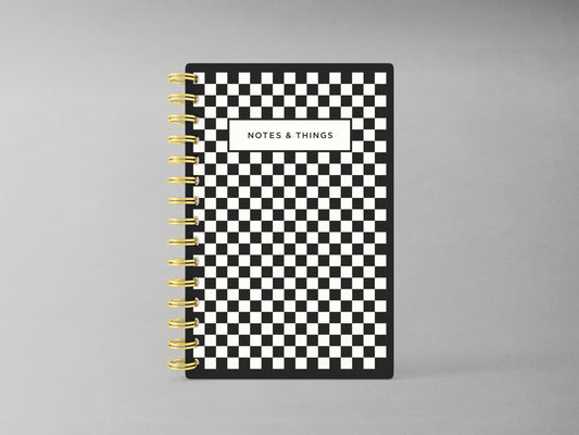 Enhance your note-taking experience with this sophisticated A5-sized hardcover spiral bound notebook, showcasing an elegant black and white checkerprint design. Accented with a luxurious gold spiral, its interior boasts blank pages, offering versatility for sketches, notes, or creative projects.