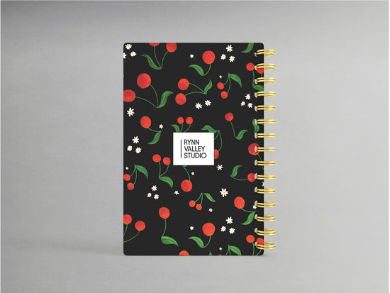 Embrace sophistication with this cherry-themed A5-sized hardcover spiral bound notebook, set against a sleek black background. Its design highlights a rich cherry motif, accented by a sturdy black spiral binding. Inside, enjoy the versatility of blank pages, ideal for jotting down notes, sketches, or creative inspirations with a touch of elegance.